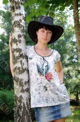 beautiful girl in the hat around birch