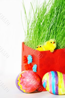 Colored easter eggs and chickens in green grass