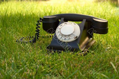 Retro styled rotary telephone in the grass Retro styled rotary telephone in the grass