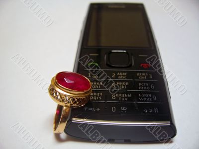 Mobile phone and golden ring with red stone