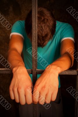 Man with hands tied with rope behind the bars