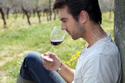 Man tasting wine in field