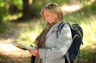 Older woman looking at a map in a forest