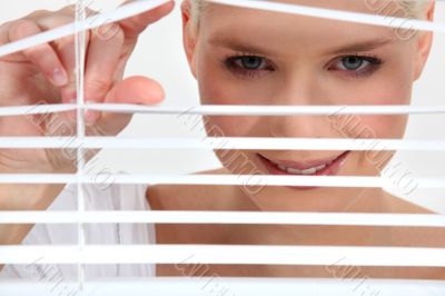 Woman peering through blinds