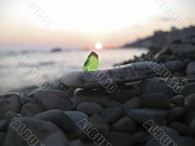 Green glass laying on the sea shore