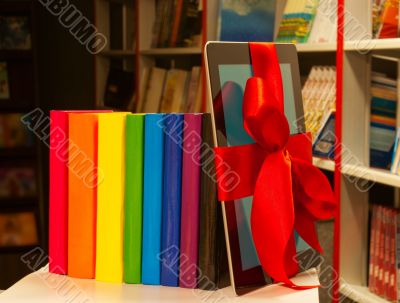 E-book tied up with red ribbon and row of books