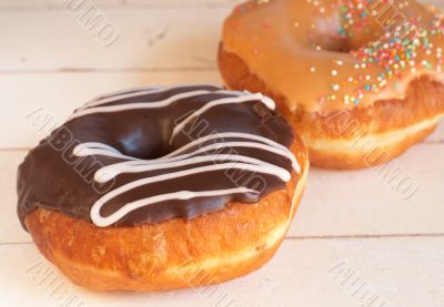 Two donuts covered in caramel and chocolate icing 