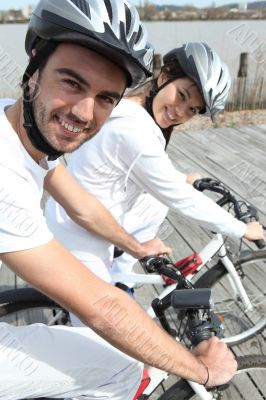 Young couple cycling alongside a river