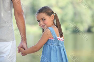 Young girl walking by the lake with her parents