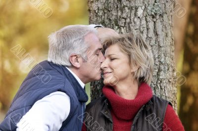 Middle-aged couple kissing by tree
