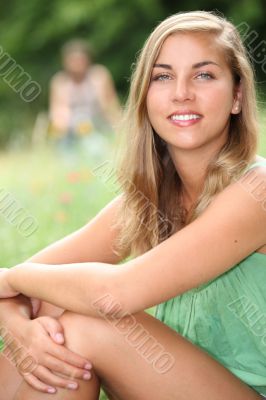 Young woman sitting in a meadow in the summertime