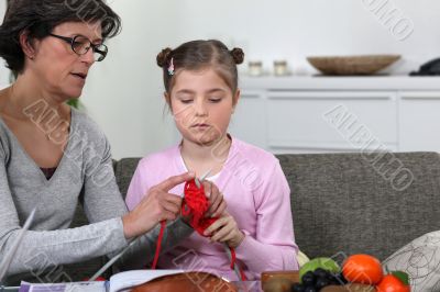 Grandmother teaching her granddaughter how to knit