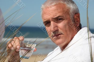 Man sat alone on beach in dressing gown