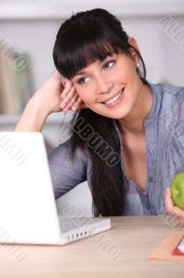 Woman working on her laptop and holding an apple