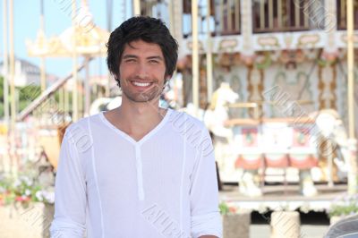 man posing in front of a carousel man posing in front of a carousel