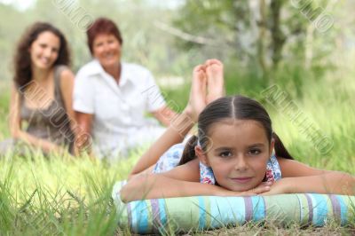 girl relaxing in park with mother and grandma