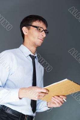 Closeup of a young smiling business man standing confidently against the wall