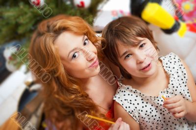 Mother and her daughter sitting together near christmas tree.