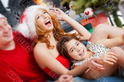 Young happy familye near a Christmas tree at home holding gifts.