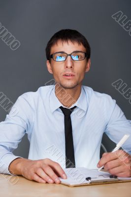 Portrait of an adult business man sitting in the office and signing documents.