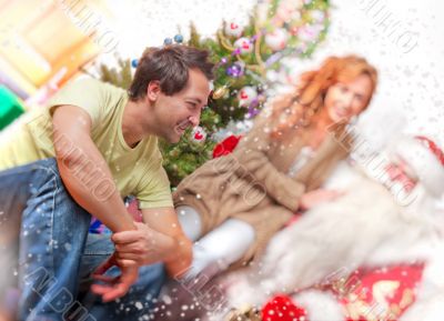 Happy family embracing and sitting on the floor in front of Christmas Tree.