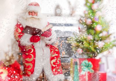 Santa sitting at the Christmas tree, near fireplace and reading a book.