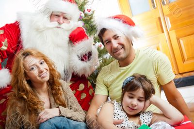 Happy family embracing and sitting on the floor in front of Christmas Tree.
