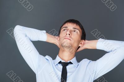 Portrait of relaxed business man against grey background. 