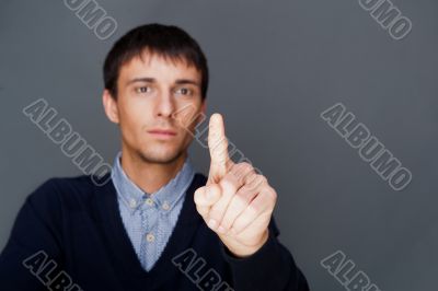 Young business man pressing a touchscreen button while working at his modern office.