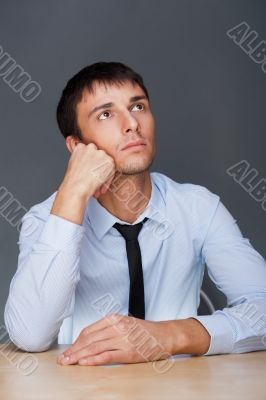 Portrait of an adult business man sitting in the office and daydreaming, planing.