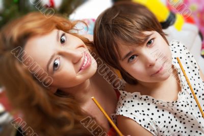 Mother and her daughter sitting together near christmas tree