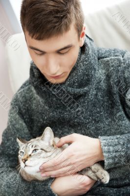 Relaxed man sitting on armchair holding and petting pet cat