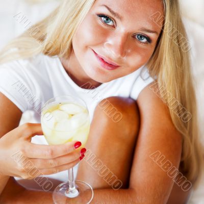 Woman drinking fresh ice tea beverage and looking at camera whil
