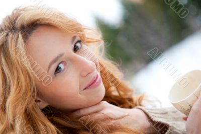 Portrait of beautiful red hair girl drinking coffee on winter ba