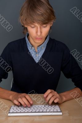Portrait of young handsome good looking man working using keyboa