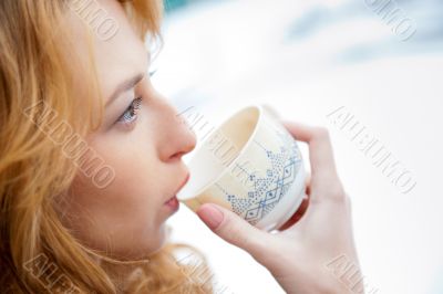 Portrait of beautiful red hair girl drinking coffee on winter ba