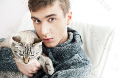 Relaxed man sitting on armchair holding and petting pet cat