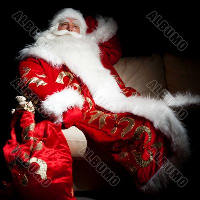 Santa sitting with a sack indoor at dark night room