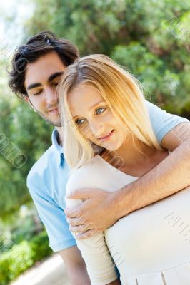 Portrait of love couple embracing outdoor in park looking happy