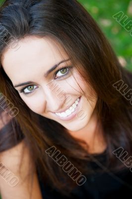 Portrait of smiling young girl sitting on grass in the forest an