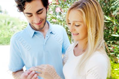 Happy young hispanic man gifting a ring to a beautiful surprised