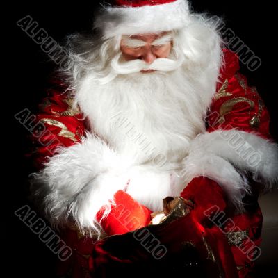 Santa sitting at the Christmas room and looking into the sack