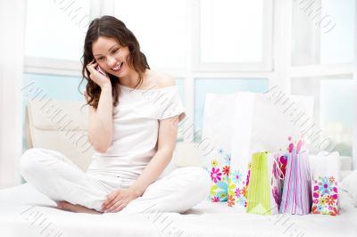 Portrait of young beautiful awake woman with gifts on bed at bed