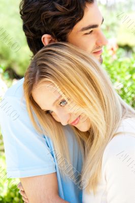 Portrait of love couple embracing outdoor in park looking happy