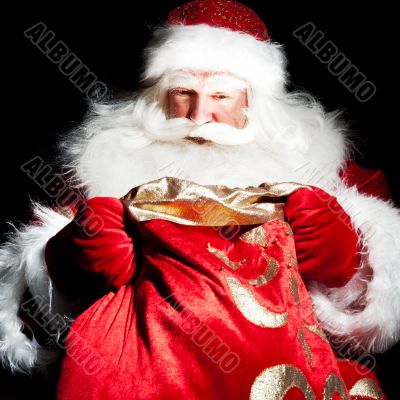 Santa sitting at the Christmas room and looking into the sack