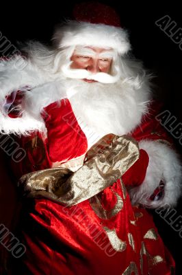 Santa sitting at the Christmas room and looking into the sack