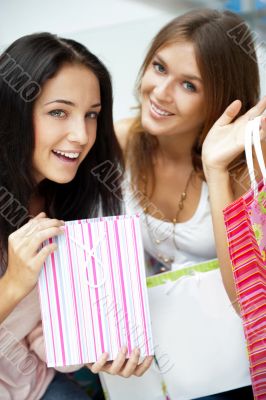 Two excited shopping woman resting on bench at shopping mall loo