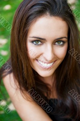 Portrait of smiling young girl sitting on grass in the forest an