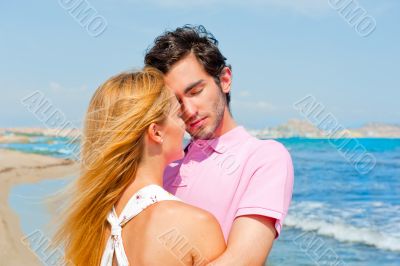 Portrait of young couple in love embracing at beach and enjoying