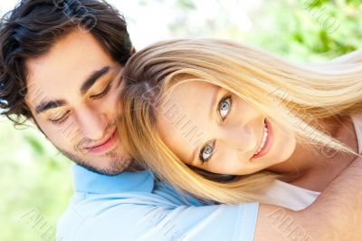 Portrait of love couple embracing outdoor in park looking happy